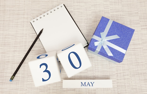 Calendar with trendy blue text and numbers for May 30 and a gift in a box.