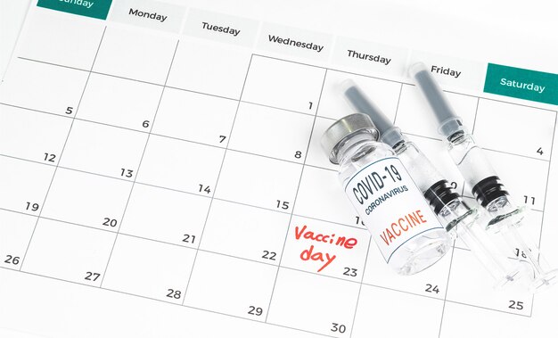 calendar with vaccination dates, a Covid-19 vaccine, and a medical concept with a syringe.