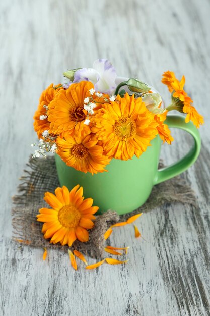 Calendula bloemen in beker op houten achtergrond