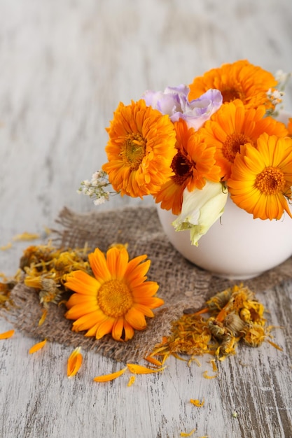 Calendula bloemen in beker op houten achtergrond