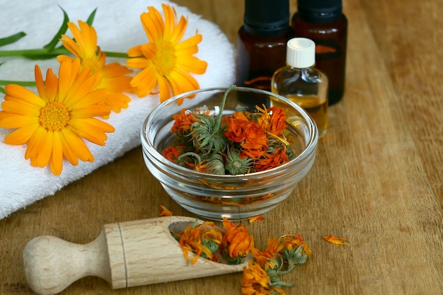 The calendula extract. Medicinal plants. Bottles and dried calendula officinalis petals with macerated oil on wooden table.