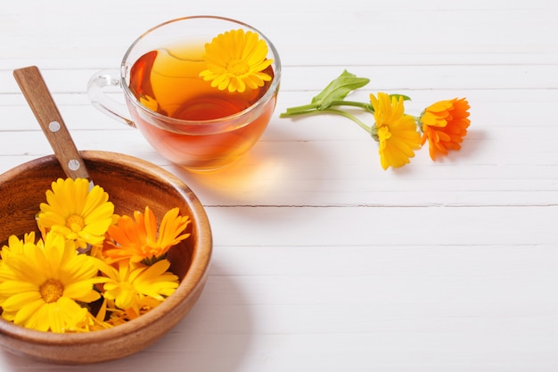 Calendula (Marigold) herbal tea on white wooden table
