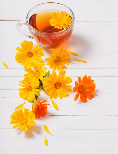 Calendula (Marigold) herbal tea on white wooden table