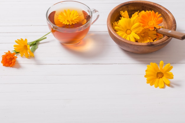 Tisana della calendula (tagete) sulla tavola di legno bianca