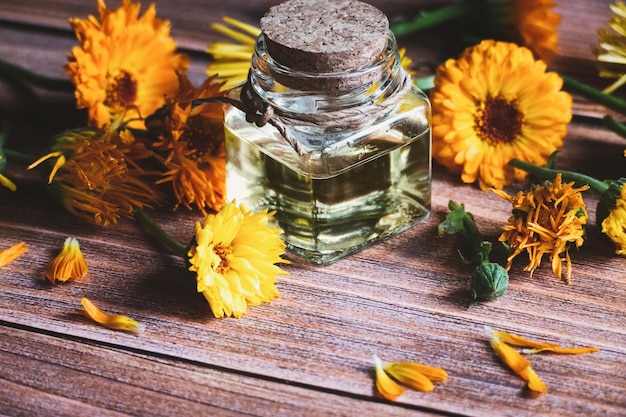 Calendula olie in glazen fles Calendula officinalis goudsbloem bloemen op houten tafel