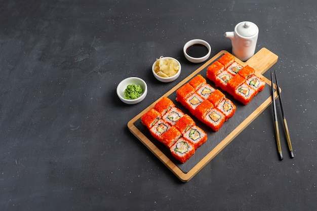 Foto california maki sushi con masago - rotolo di polpa di granchio, avocado, cetriolo all'interno.