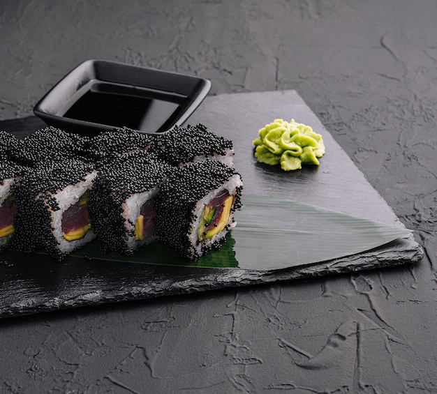 California rolls covered black tobiko on a black board