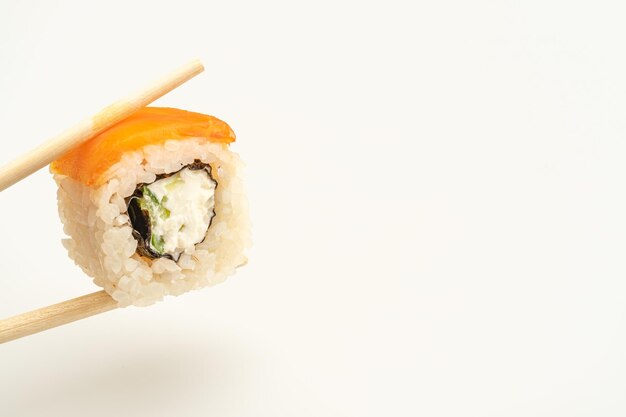 Il sushi californiano si tiene con le bacchette di legno su uno sfondo bianco isolato