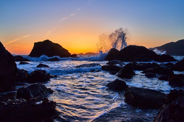 Californisch strand op gouden uur met golven die over rotsen beuken
