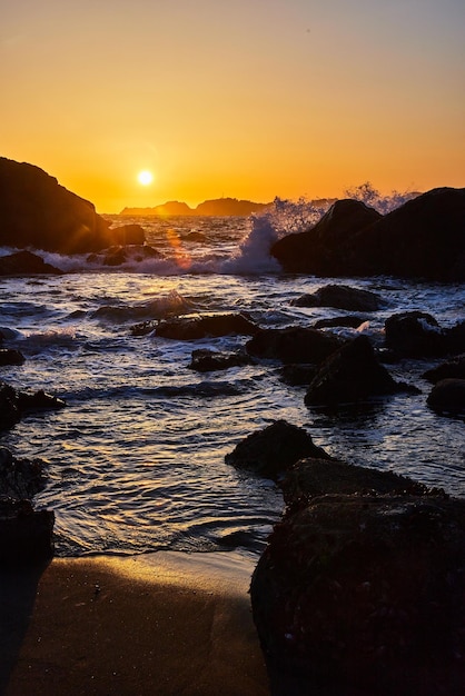 Californische stranden met oceaangolven die tijdens zonsondergang over rotsen beuken