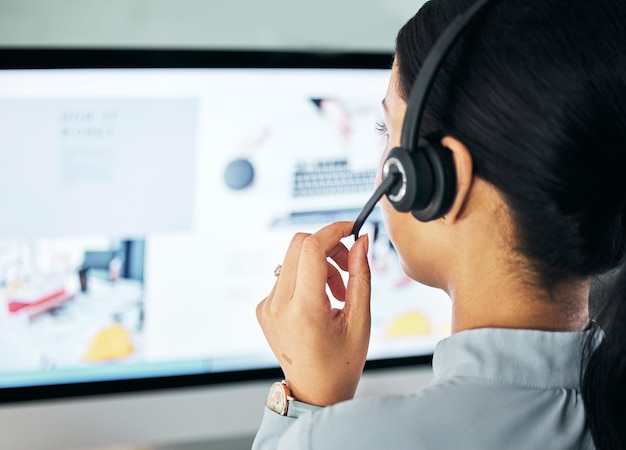 Call center agent giving online support with computer screen working as advisor and doing telemarketing in an office at work from behind Closeup of customer service representative talking with pc