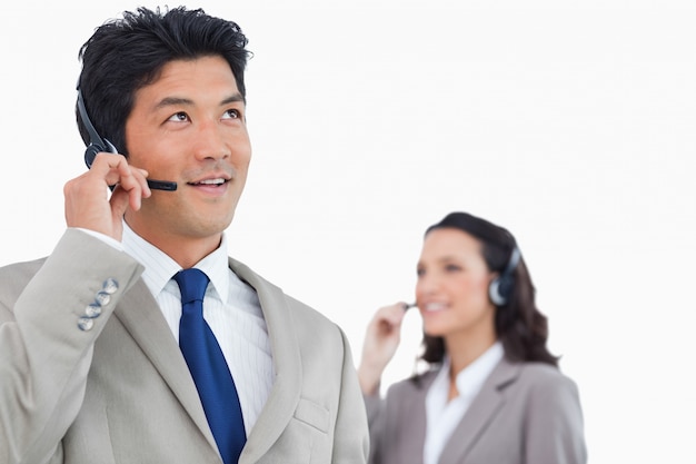 Call center agent met headset en collega achter hem