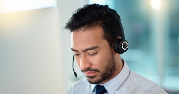 Photo call center agent talking and listening to a client on a headset while working in an office confident and reassuring salesman consulting and operating a helpdesk for customer service and support