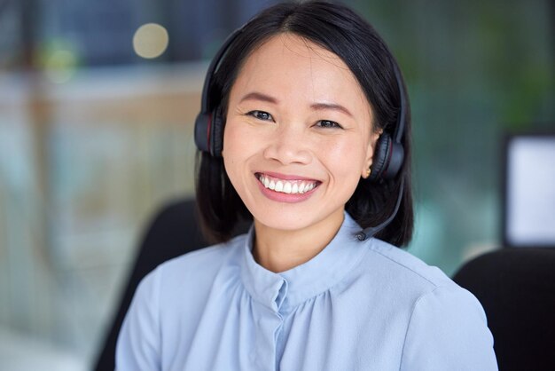 Call center asian woman and sales consultant with a smile for sales customer support and telemarketing at office for friendly service Portrait of happy contact us CRM and telecom service agent