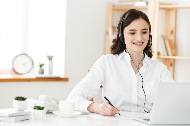 Call center concept: ritratto di felice sorridente operatore telefonico di assistenza clienti femminile sul posto di lavoro.