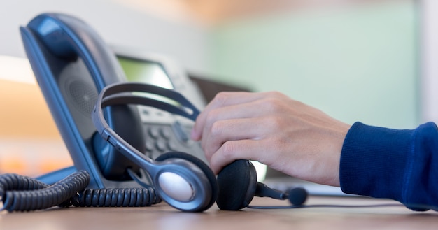 Photo call center employee man hand holding headset on telephone