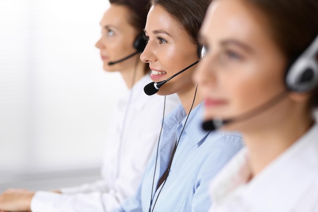 Call center. Group of operators at work. Focus at beautiful business woman in headset.