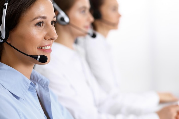 Call center. Group of operators at work. Focus on beautiful business woman in headset.
