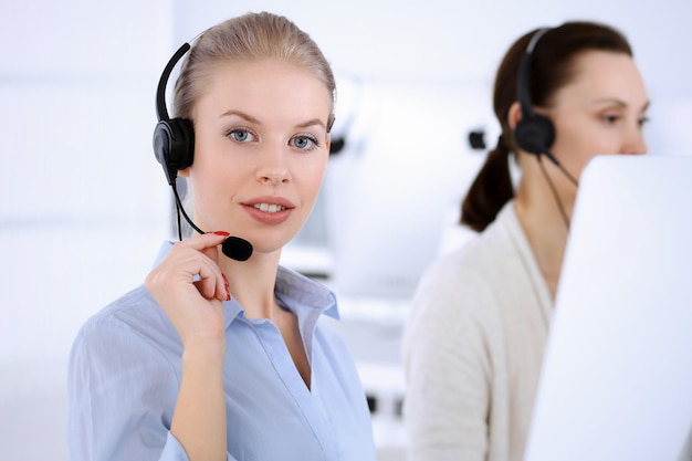 Ufficio del call center bella donna bionda che usa computer e cuffie per consultare i clienti online gruppo di operatori che lavorano come occupazione del servizio clienti concetto di uomini d'affari