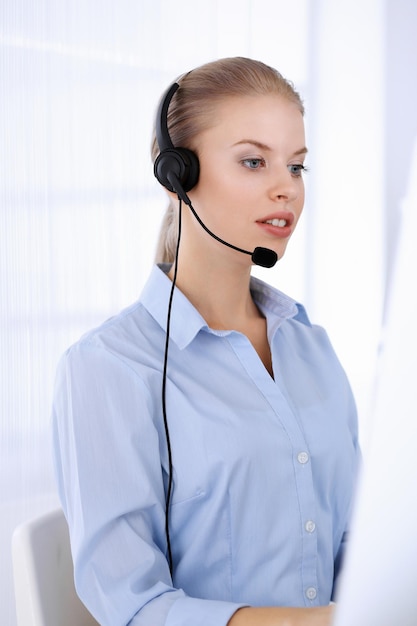 Call center office Beautiful blonde woman using computer and headset for consulting clients online Group of operators working as customer service occupation Business people concept