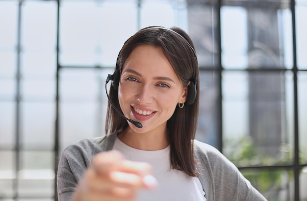 Call center operator woman pointing with finger to the camera and to you hand sign positive and confident gesture from the front