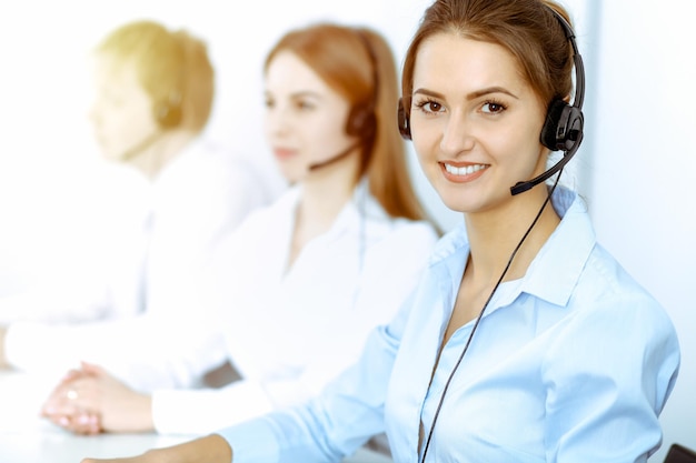 Call center operators. Focus on beautiful business woman in headset.