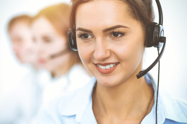 Call center operators. Focus on beautiful business woman in headset.