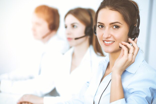 Call center operators. Focus on beautiful business woman in headset.