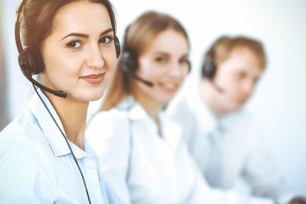 Call center operators. Focus on beautiful business woman in headset.