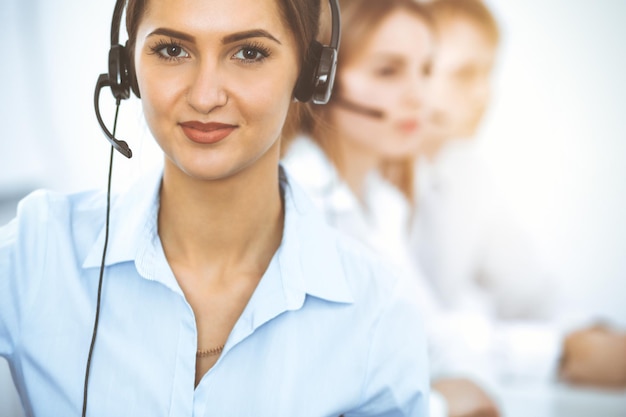 Call center operators. Focus on beautiful business woman in headset.