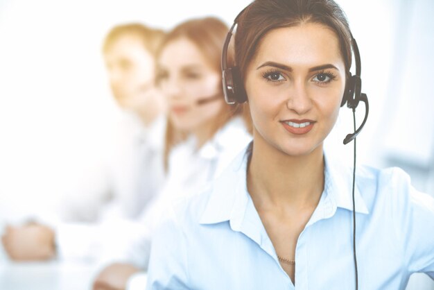 Call center operators. Focus on beautiful business woman in headset.