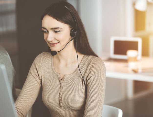 Call center operators at work. Two young people in headsets are talking to the clients, while sitting in sunny office.