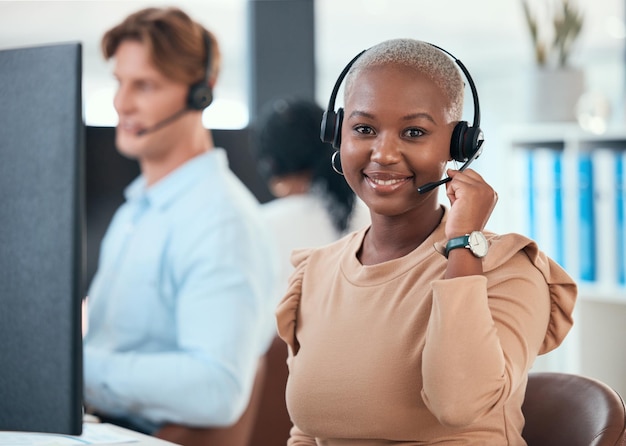 Call center woman telemarketing and customer service consultant wearing a headset and looking happy at her office desk Contact us and crm agent offering support and friendly service with a smile