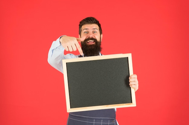 Call for delivery mature man red background happy hipster bartender Restaurant menu cafe shop advertisement Happy hours bearded man show chalkboard copy space brutal waiter in kitchen