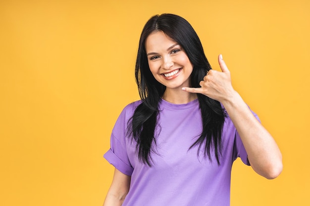 Call me baby Portrait of happy smiling brunette girl in casual isolated over yellow background