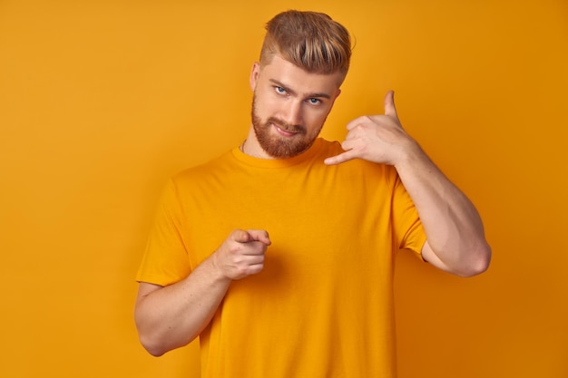 Photo call me back please. young attractive blonde guy with red beard, makes phone sign