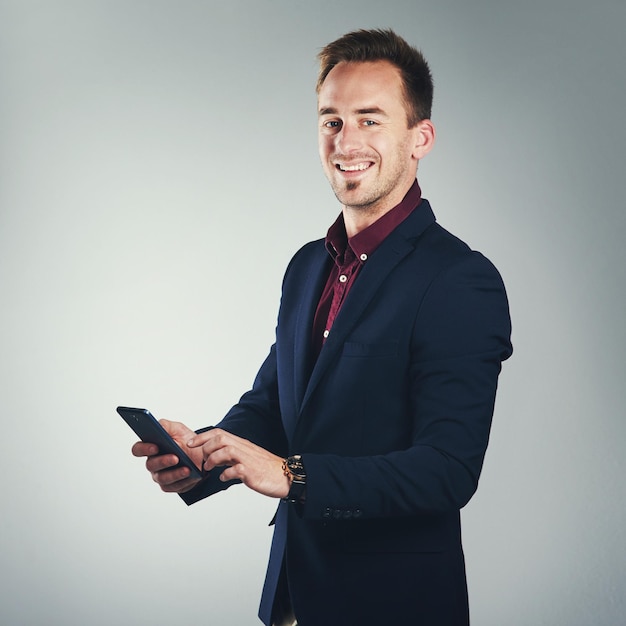 Call me and connect with the best Studio portrait of a confident young businessman using a mobile phone against a gray background