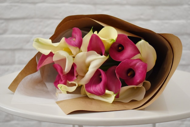 Callas in packing paper. Concept of flower salon