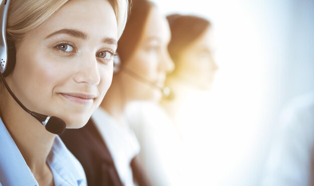 Callcenter en mensen uit het bedrijfsleven concept. Mooie zakenvrouw die met hoofdtelefoons cliënten raadpleegt. Groep diverse telefoonexploitanten op het werk in bureau.