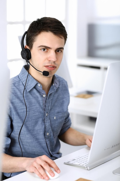 Callcenter. Focus op jongeman receptioniste in headset bij klantenservice