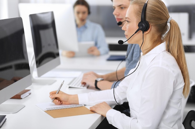 Foto callcenter groep casual geklede operators op het werk focus op zakenvrouw in headset op klantenservicekantoor telesales in business