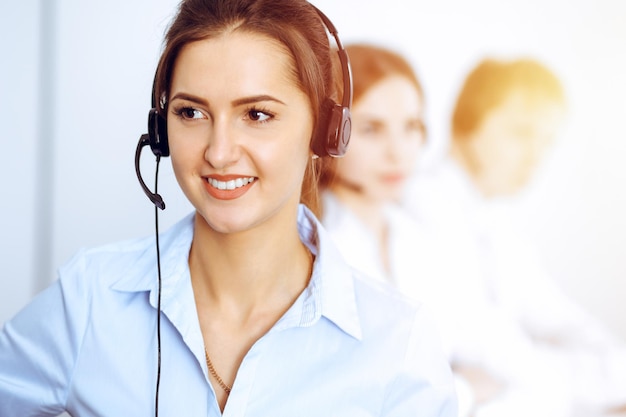 Callcenter operators. Focus op mooie zakenvrouw met behulp van headset in zonnig kantoor.