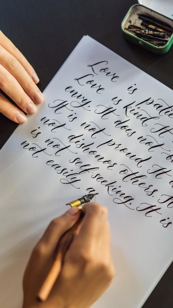 写真 書道家の手は、装飾用の愛を刻むことについての白い紙の聖書のフレーズにフレーズを書きます