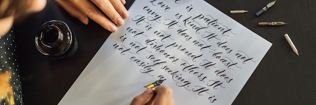 Foto le mani del calligrafo scrivono una frase su una frase biblica di carta bianca sull'amore che inscrive ornamentale