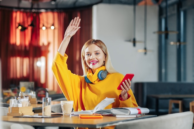 Calling for waiter Blondehaired stylish woman raising her hand while calling for waiter