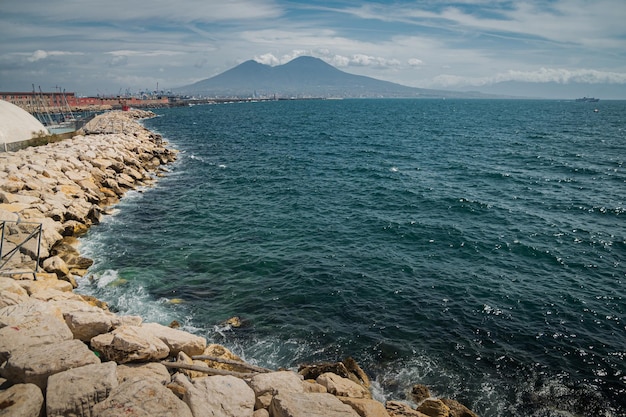 Calm blue Tyrrhenian Sea View from the embankment of Naples to Mount Vesuvius volcano Stone breakwater curves along the sea