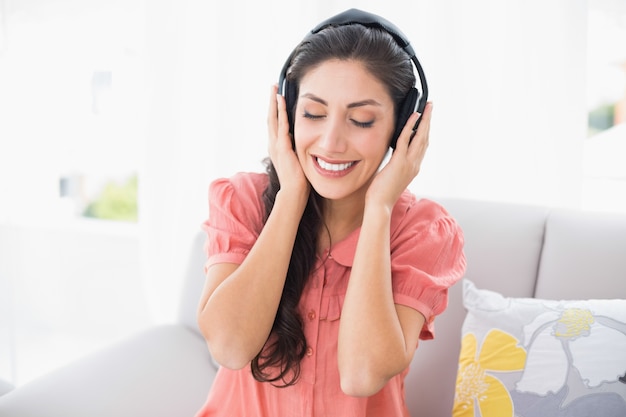 音楽を聴いているソファに座っている静かなブルネット