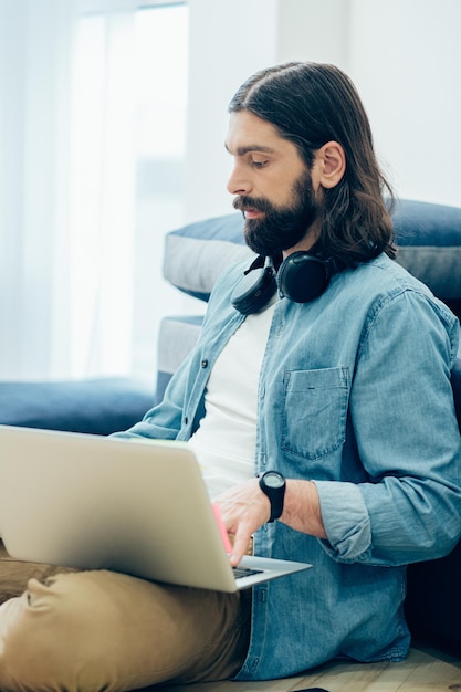 Calm concentrated man sitting alone in casual clothes and using laptop for distant work