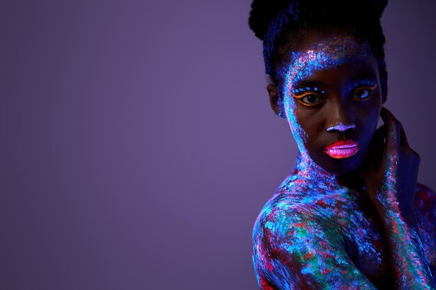 Sensual woman with black skin in fluorescent paint makeup, posing at camera  Stock Photo by ©ufabizphoto 535506164