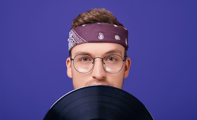 Calm guy with glasses and a bandana with a record player.